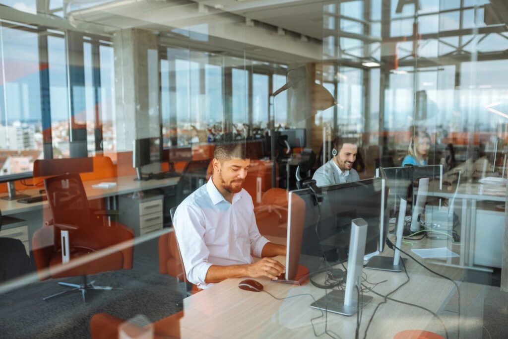 A man sitting at his desk in front of two monitors.